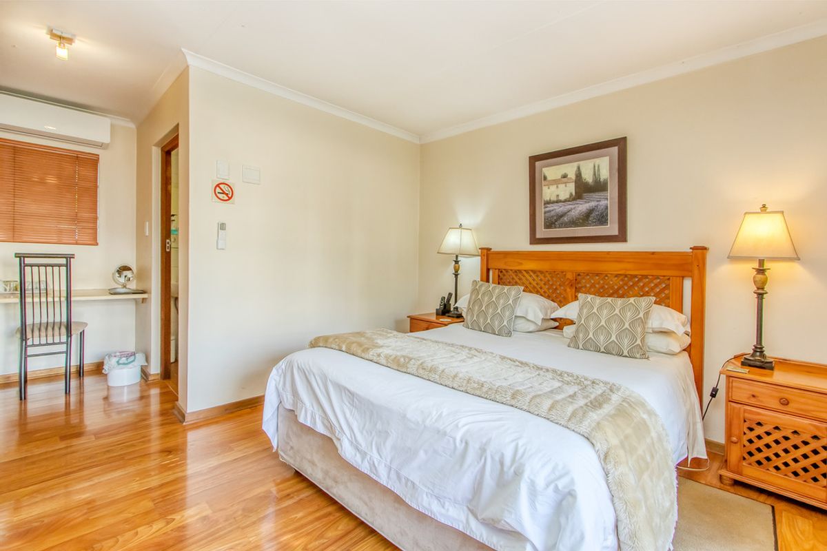 A well-maintained bedroom featuring warm laminate flooring, a built-in desk area, and a split-system air conditioning unit for climate control.