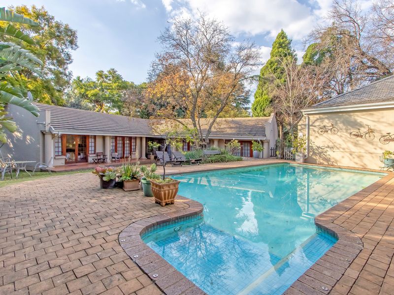 A spacious outdoor pool area featuring a paved patio, swimming pool, and direct access to the guest house through multiple sets of french doors.
