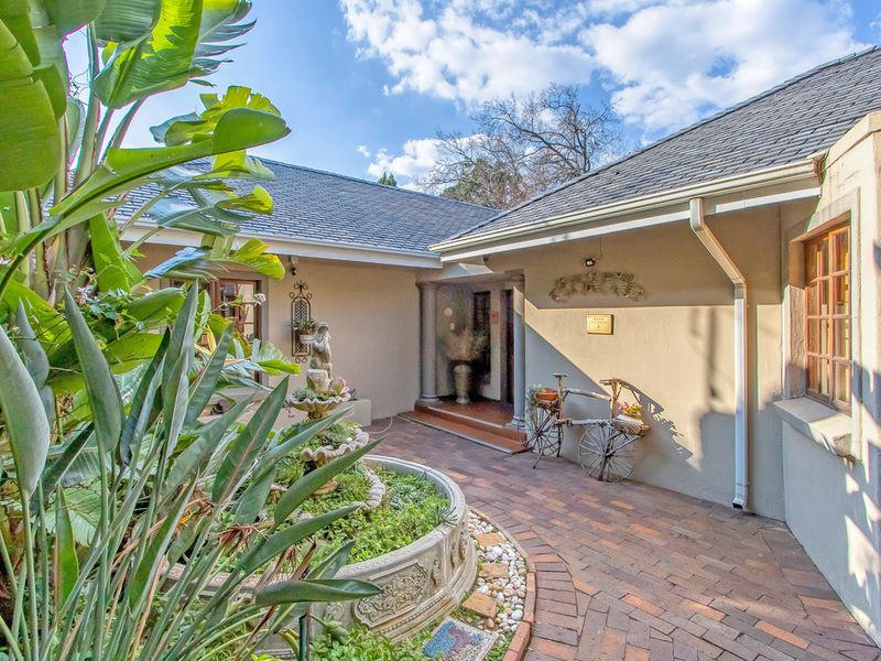 A charming guest house entrance featuring brick paving, a stone fountain, and a well-maintained exterior facade with a tiled roof.