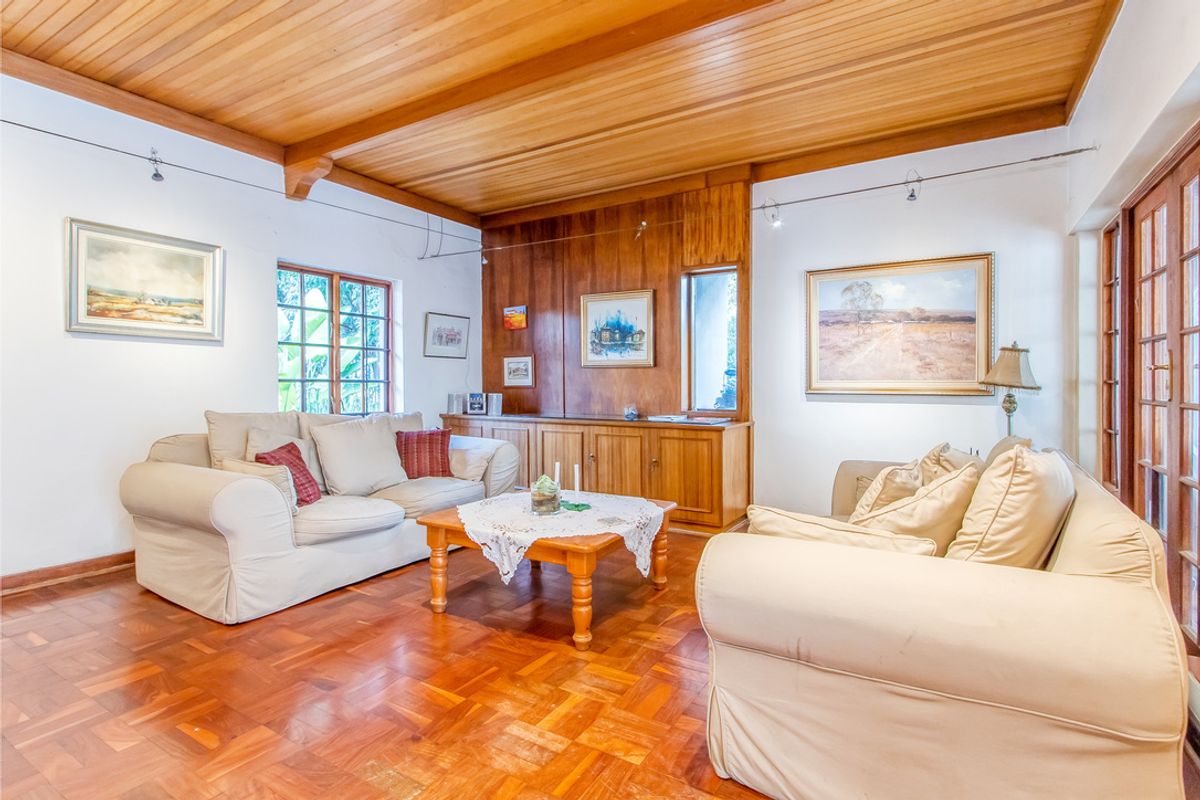 A warm living room featuring classic parquet flooring, a timber-paneled ceiling, and built-in wooden cabinetry, offering a cozy and traditional atmosphere.