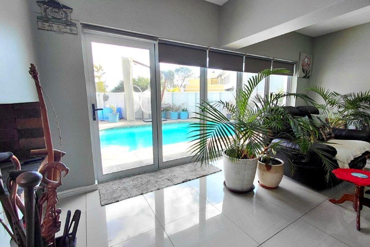 Bright living area featuring large sliding glass doors that provide direct access to the outdoor swimming pool and patio area.