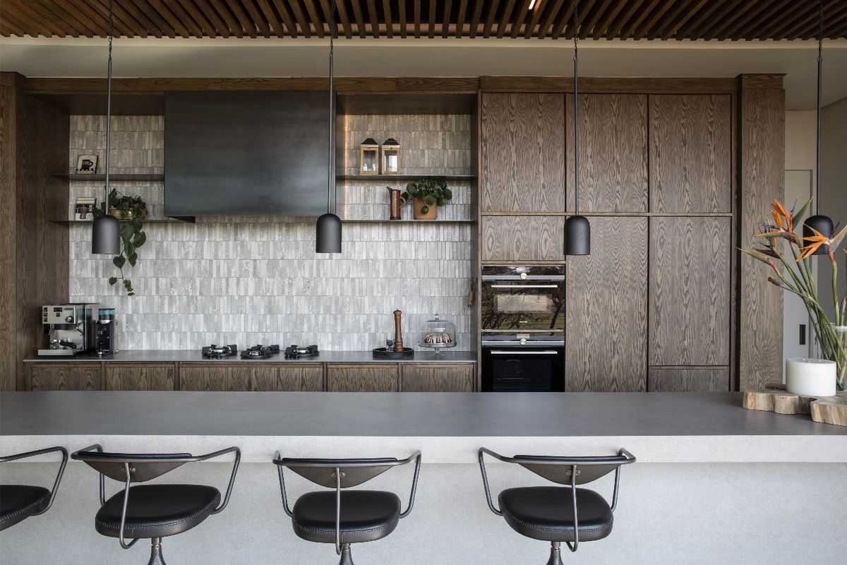 Modern kitchen featuring high-end timber cabinetry, integrated oven, gas cooktop, stone island bench, and a stylish slatted timber ceiling.