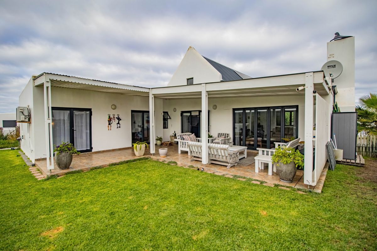 A spacious rear patio area featuring a covered pergola, tiled flooring, and direct access to the home through multiple glass sliding doors.