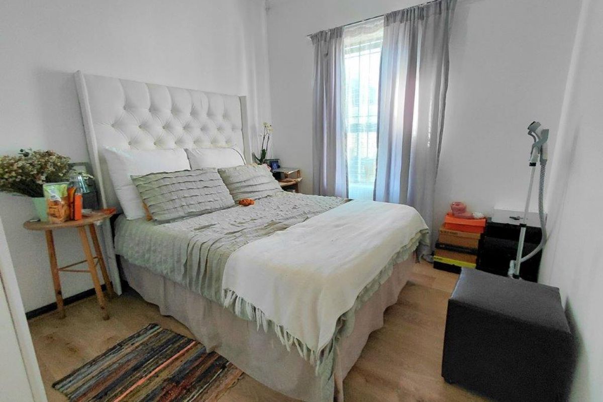 A well-lit bedroom featuring light wood-look flooring and neutral walls, providing a comfortable and functional living space.