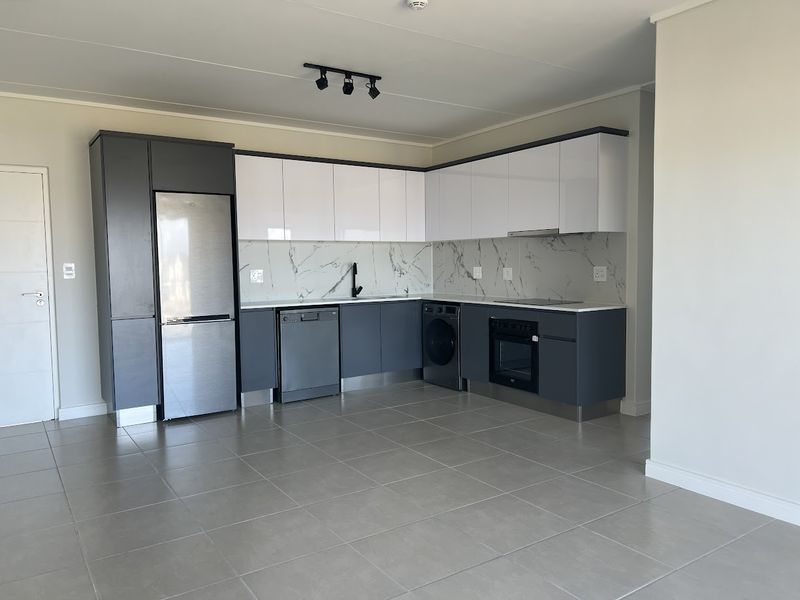 Modern kitchen featuring sleek two-tone cabinetry, marble-look splashback, integrated oven, cooktop, and tiled flooring in an open-plan layout.
