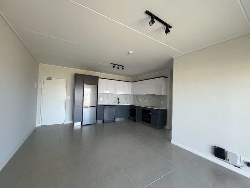 Modern open-plan kitchen featuring sleek two-tone cabinetry, marble-look splashback, integrated appliances, and neutral tiled flooring in a bright, contemporary living space.