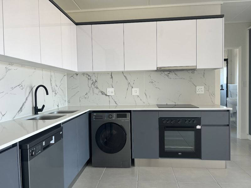 Modern kitchen featuring sleek white and grey cabinetry, marble-look splashback, stone countertops, and integrated appliances including an oven, hob, and extractor fan.