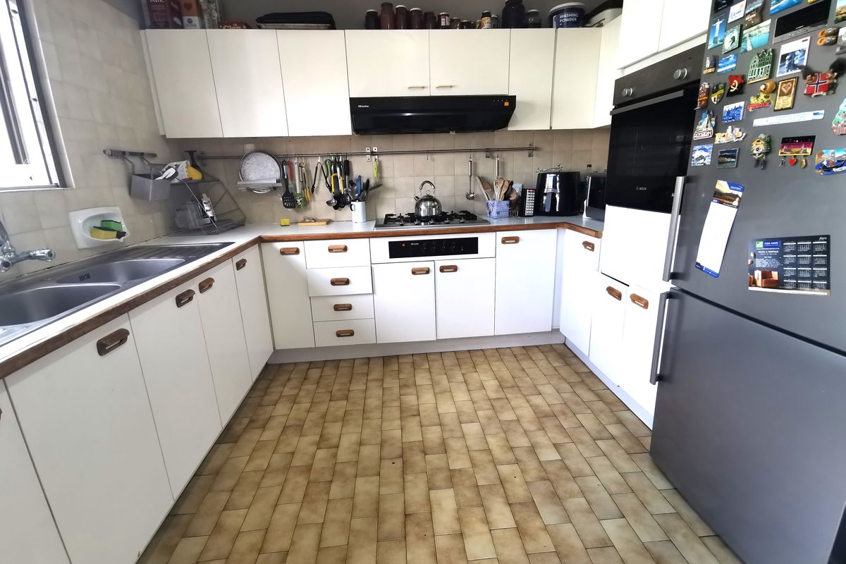 A functional kitchen featuring white cabinetry, a built-in oven, gas hob, extractor fan, and double stainless steel sink with tiled splashbacks.