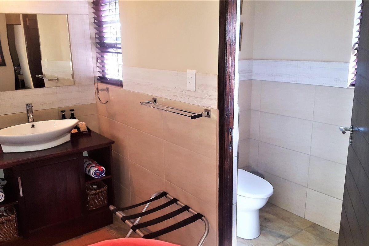 A functional bathroom featuring a vessel sink vanity, tiled walls, and a separate enclosed toilet area with neutral finishes.