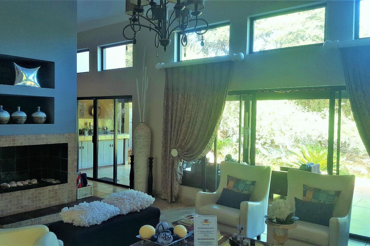 Spacious living area featuring a built-in fireplace with tiled surround, high ceilings with clerestory windows, and large sliding glass doors opening to the garden.