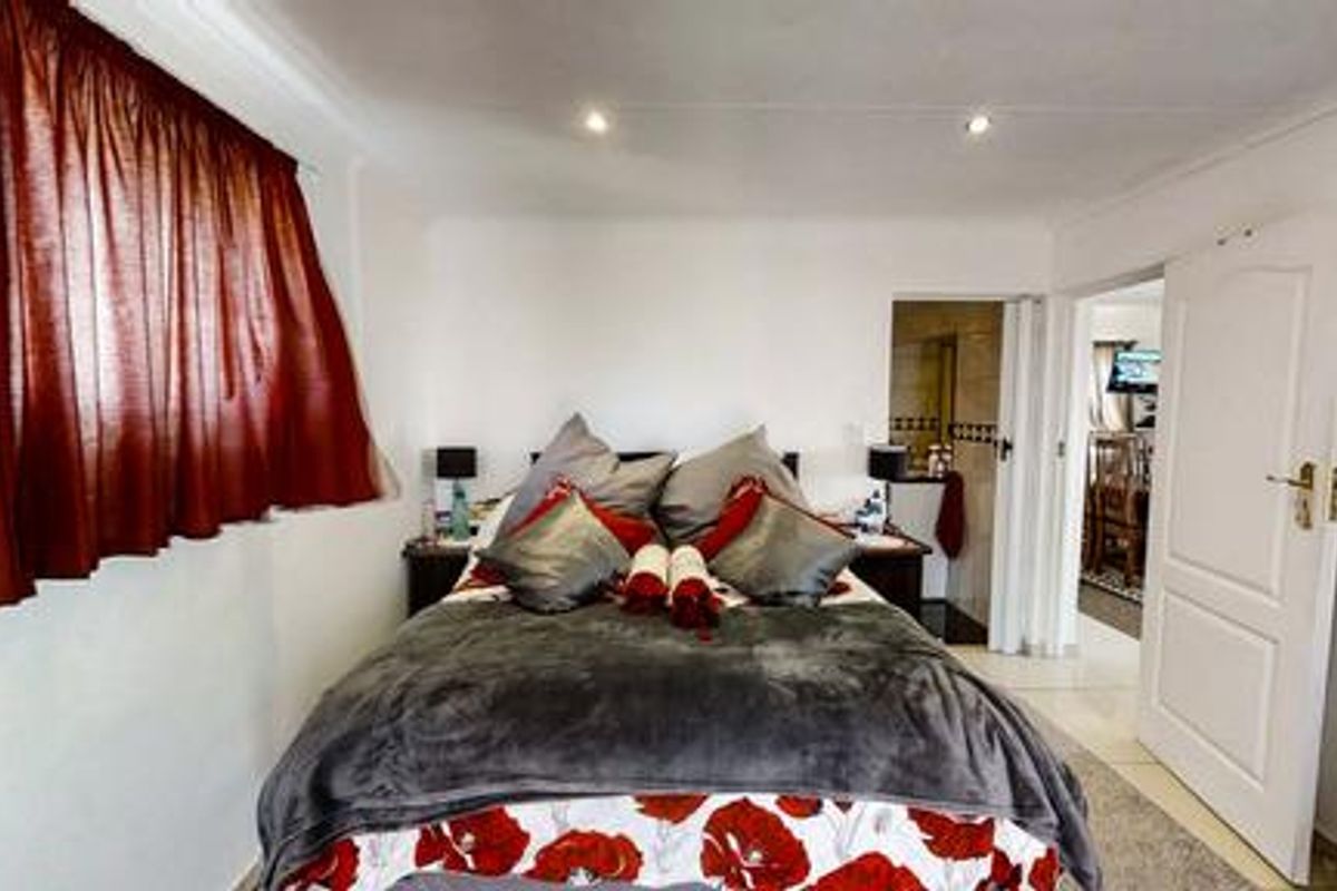 A well-lit bedroom featuring recessed ceiling lighting, neutral wall finishes, and an adjoining en-suite bathroom, providing a comfortable and functional living space.