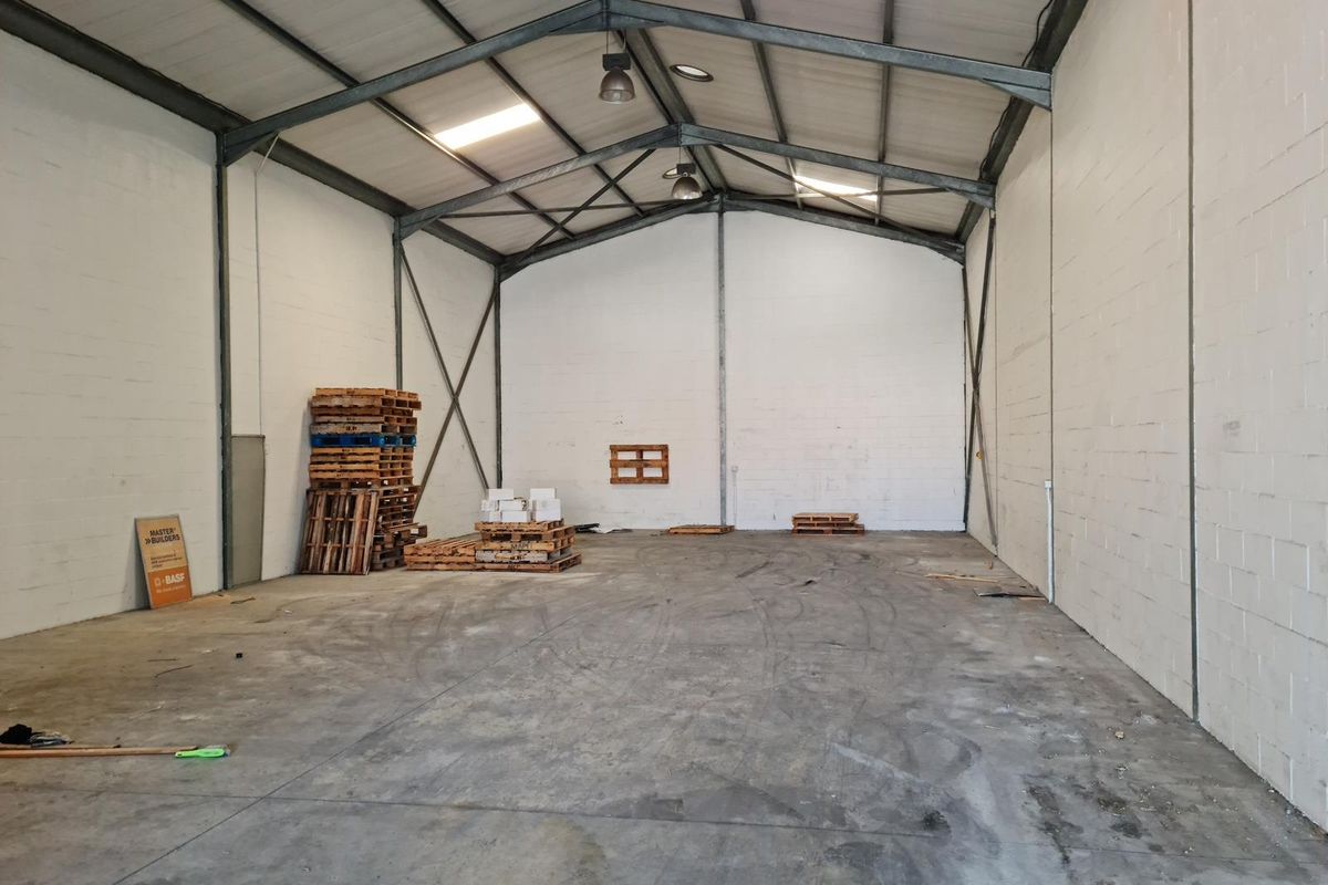Spacious industrial warehouse unit featuring exposed steel portal frame construction, concrete flooring, painted blockwork walls, and natural light provided by integrated skylights.