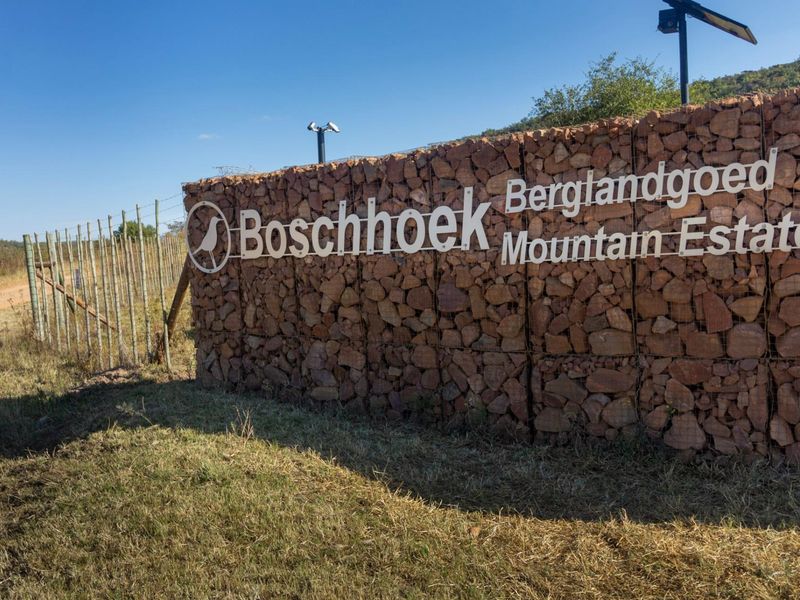 Entrance signage and gabion wall feature for Boschhoek Mountain Estate, featuring security fencing and surveillance infrastructure.
