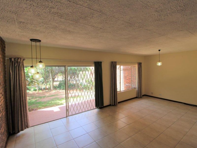 Spacious living area featuring tiled floors, an exposed brick feature wall, and large sliding doors providing direct access to the garden.
