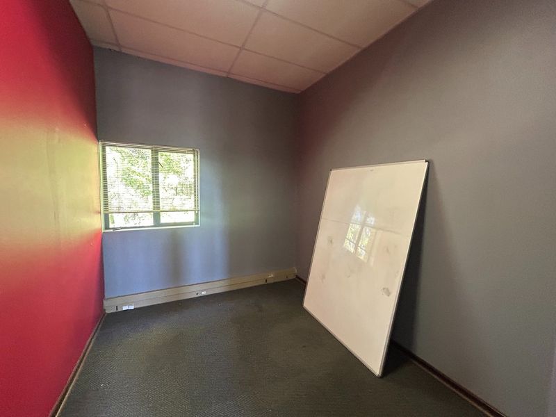 A vacant office space featuring carpet flooring, a suspended ceiling, and a window with fitted blinds, ready for professional customization.