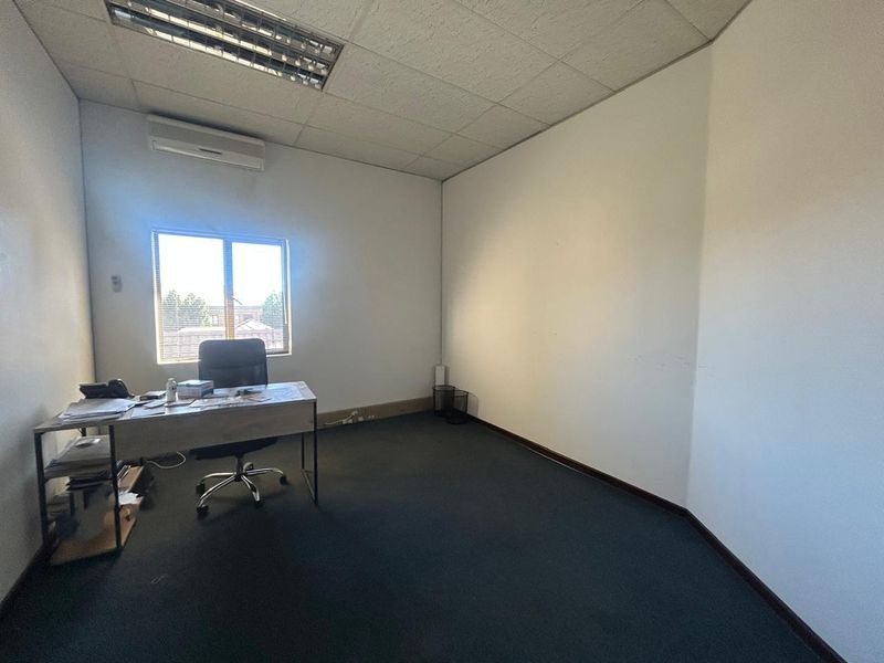 A functional office space featuring a suspended ceiling, split-system air conditioning, and carpeted flooring, providing a practical environment for professional use.