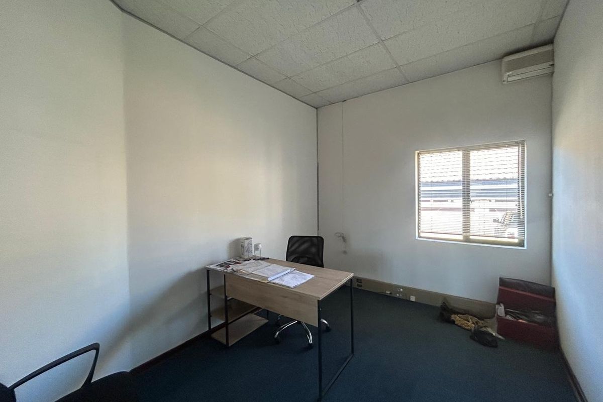 A functional office space featuring a suspended ceiling, air conditioning unit, and carpet flooring, providing a practical environment for professional use.