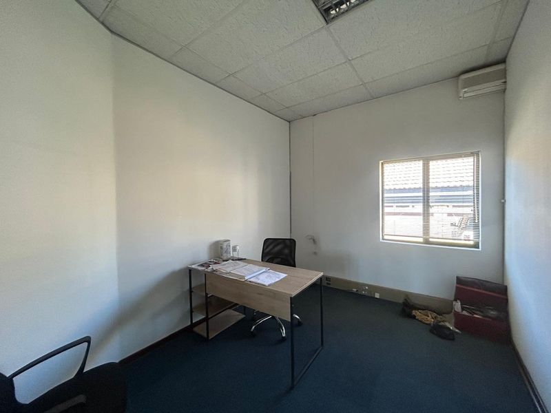 A functional office space featuring a suspended ceiling, air conditioning unit, and carpet flooring, providing a practical environment for professional use.
