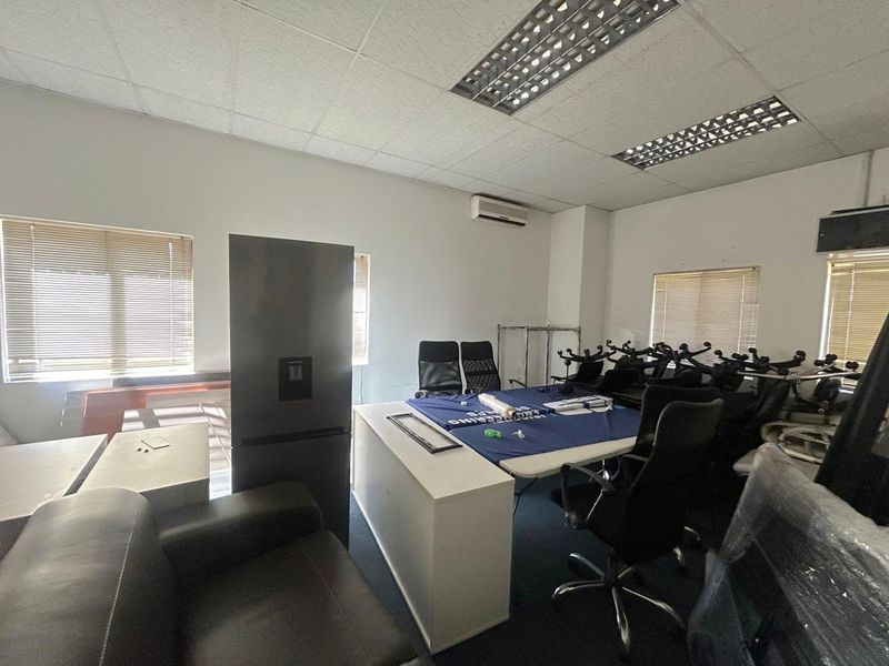 A functional office space featuring a suspended ceiling with recessed lighting, split-system air conditioning, and multiple windows fitted with venetian blinds.