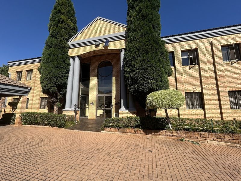 Front elevation of a professional office building featuring a brick facade, prominent columns, and a paved driveway entrance.