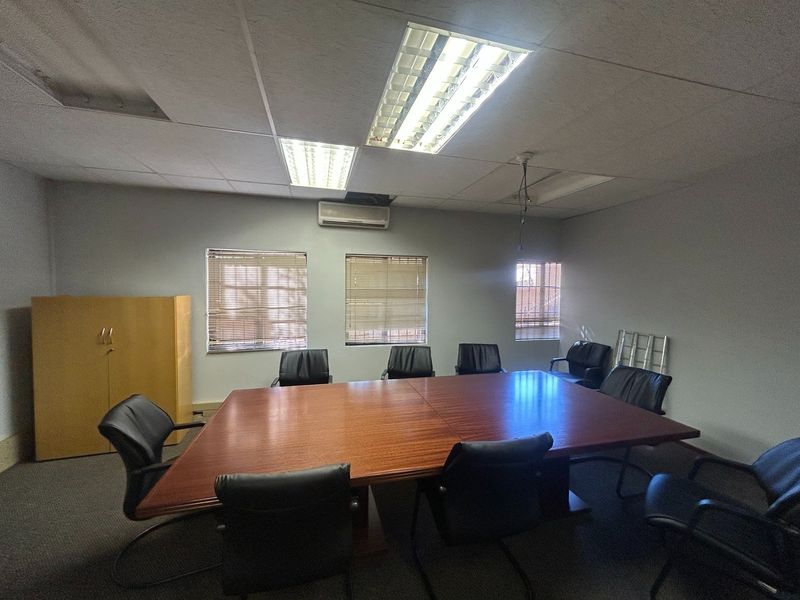 A functional office meeting room featuring a suspended ceiling, integrated air conditioning, and built-in storage cabinetry.