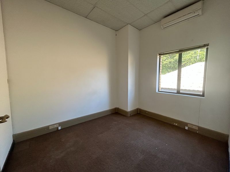 A vacant office space featuring a suspended ceiling, split-system air conditioning, and carpeted flooring, offering a clean and functional environment for professional use.