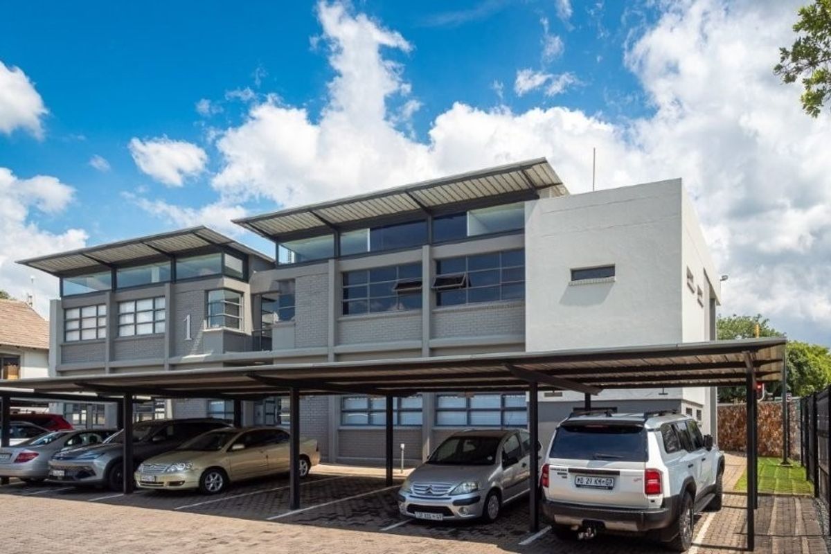 Modern multi-level office building featuring a contemporary facade with clerestory windows and extensive covered parking facilities.
