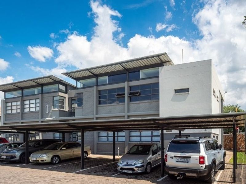 Modern multi-level office building featuring a contemporary facade with clerestory windows and extensive covered parking facilities.