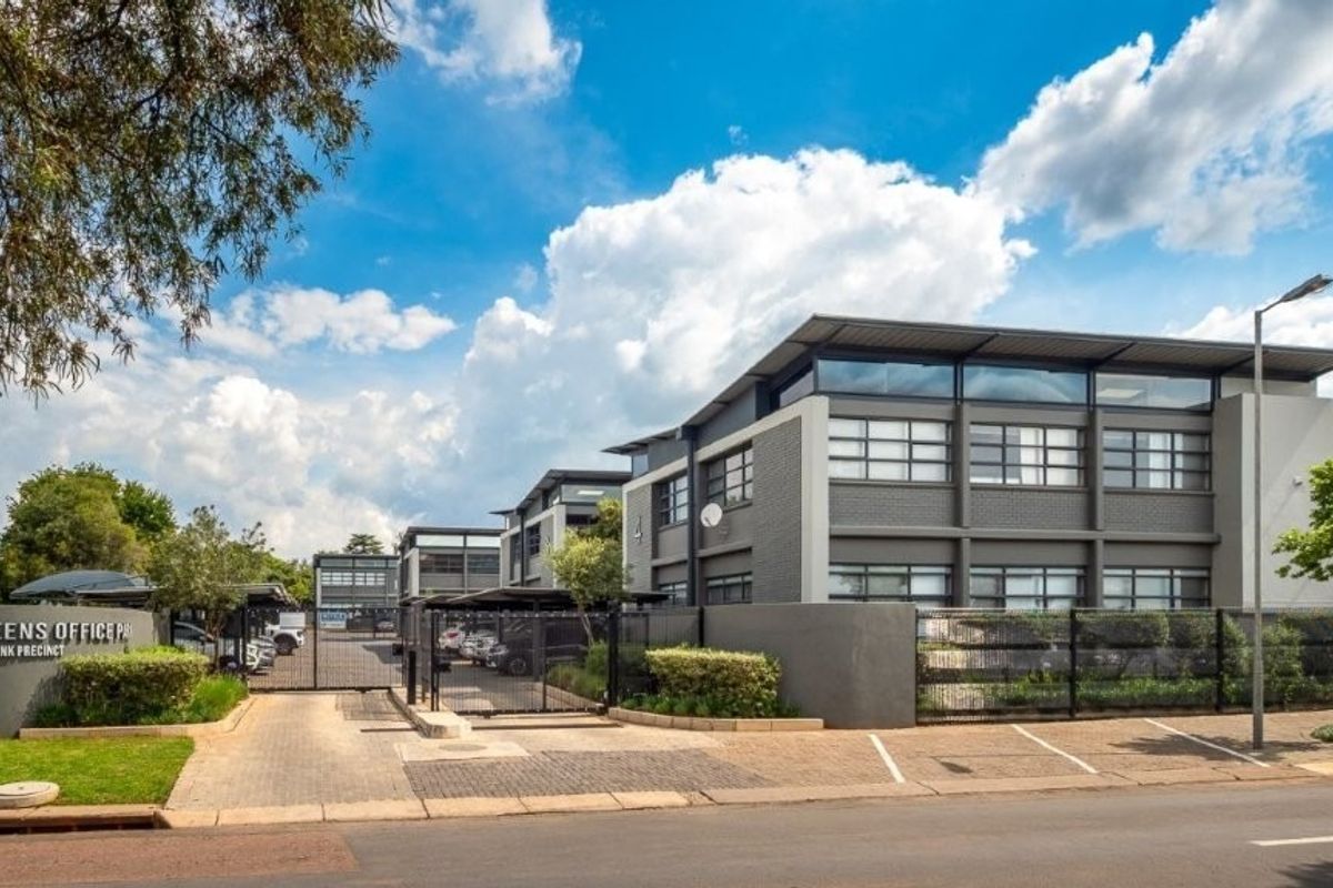 A professional exterior view of the Queens Office Park, featuring modern architecture, secure gated access, paved parking areas, and well-maintained landscaping.