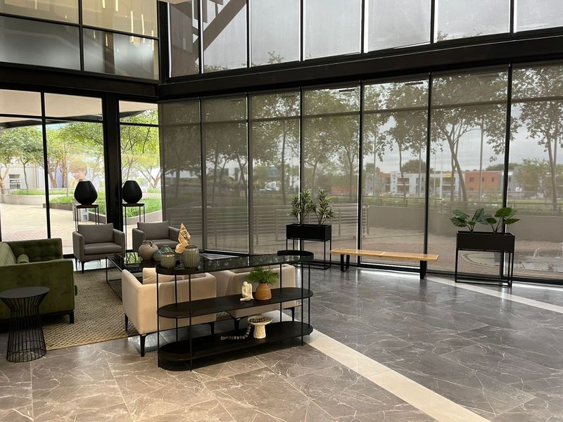 Modern office reception or lounge area featuring expansive floor-to-ceiling windows, sleek marble flooring, and high-quality black metal framing.