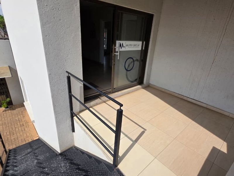 Exterior entrance area featuring tiled flooring, a sliding glass door, and metal staircase access.