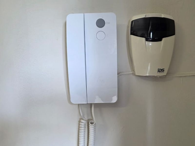 Wall-mounted intercom unit and security alarm system keypad installed in the office space.
