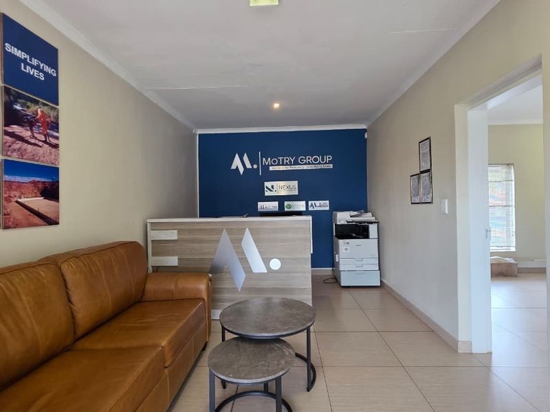 A professional office reception area featuring tiled flooring, a built-in reception desk, and a clean, branded feature wall.