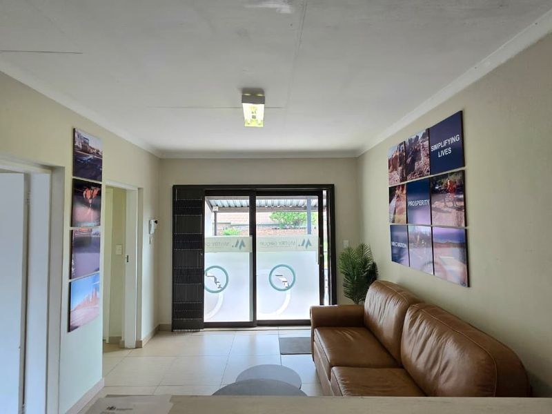 A functional office reception area featuring tiled flooring, a sliding glass door entrance, and neutral wall finishes.