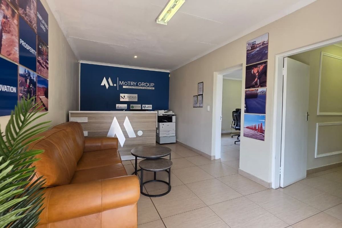 A professional office reception area featuring a branded reception desk, tiled flooring, and access to adjacent office spaces.