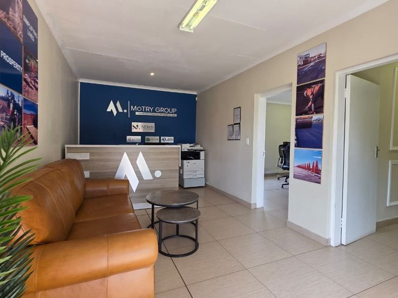 A professional office reception area featuring a branded reception desk, tiled flooring, and access to adjacent office spaces.