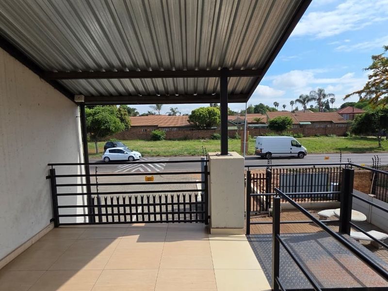 A covered outdoor balcony area featuring tiled flooring, metal security railings, and electric fencing, overlooking the street.