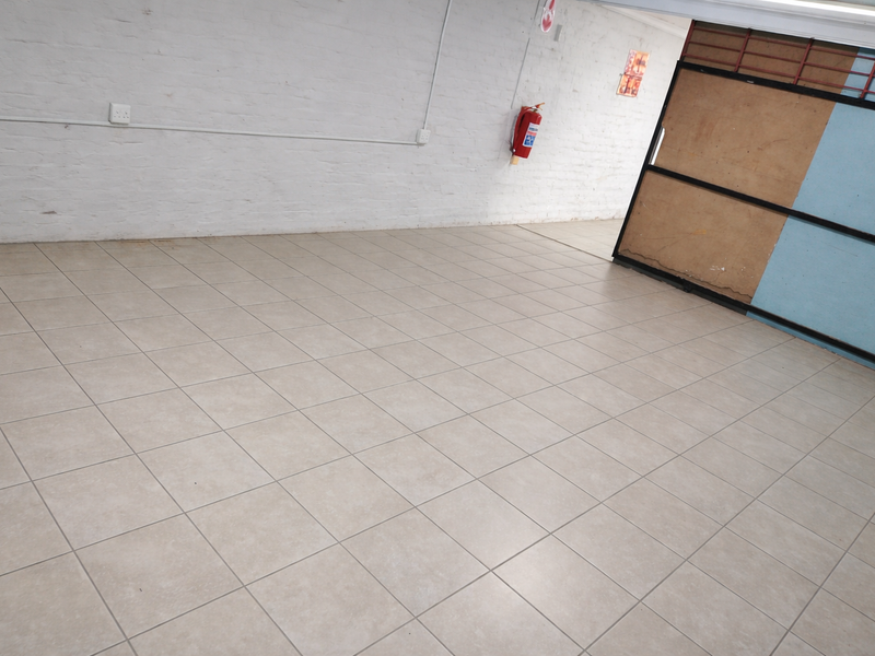 An open-plan utility or industrial space featuring tiled flooring, painted brick walls, and a wall-mounted fire extinguisher.