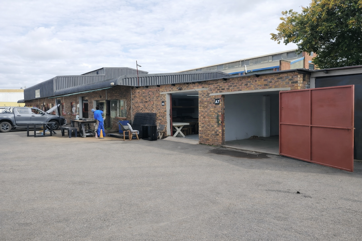 Front exterior view of an industrial property featuring brick facade, metal roofing, and large access gates for vehicle or equipment entry.