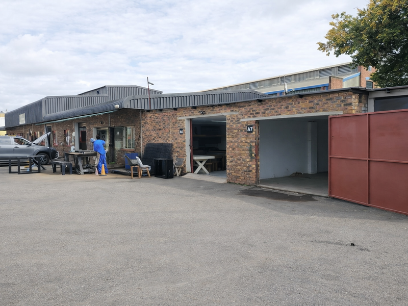 Front exterior view of an industrial property featuring brick facade, metal roofing, and large access gates for vehicle or equipment entry.