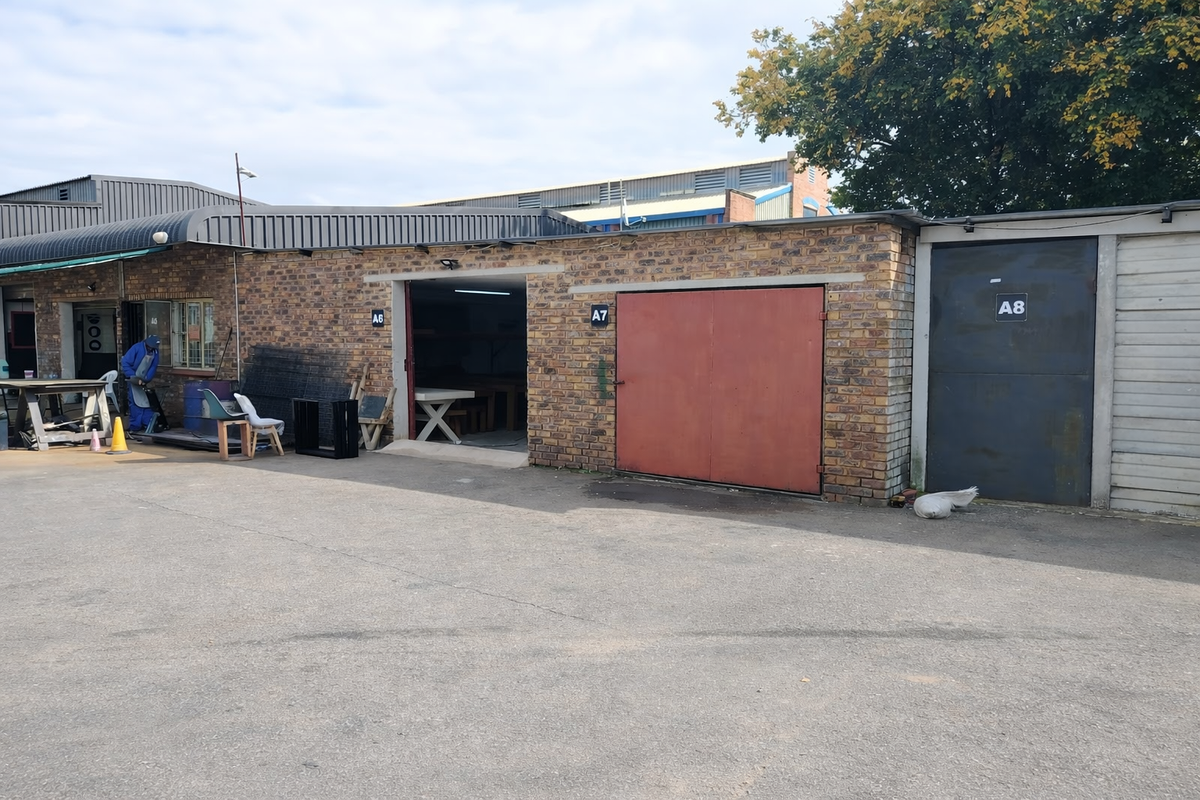 Exterior view of an industrial property featuring multiple unit access points with brick facade and metal doors.