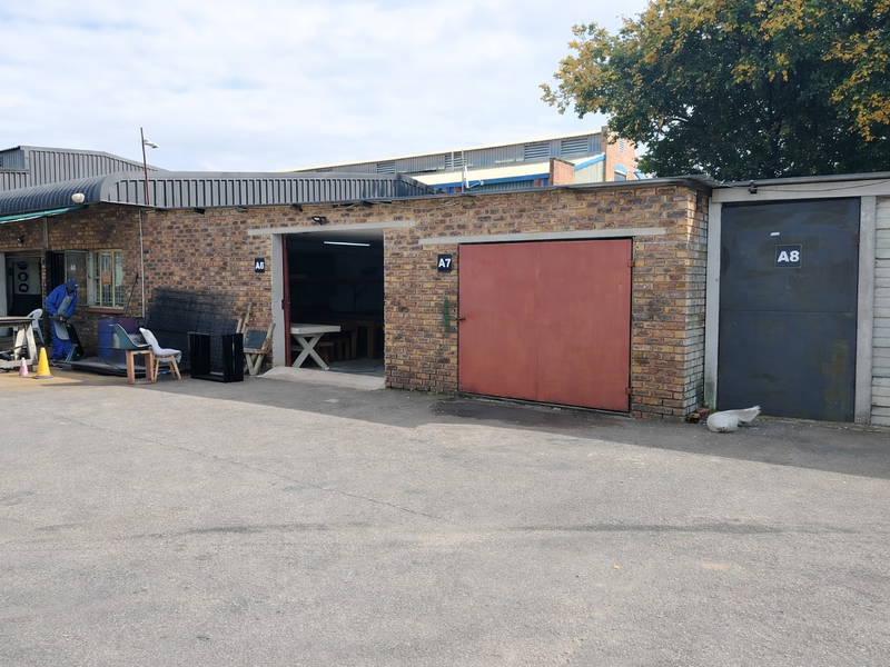 Exterior view of an industrial property featuring multiple unit access points with brick facade and metal doors.