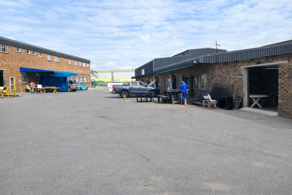 Spacious industrial yard area featuring brick-faced warehouse buildings with metal roofing and multiple access points, suitable for various commercial or light industrial operations.