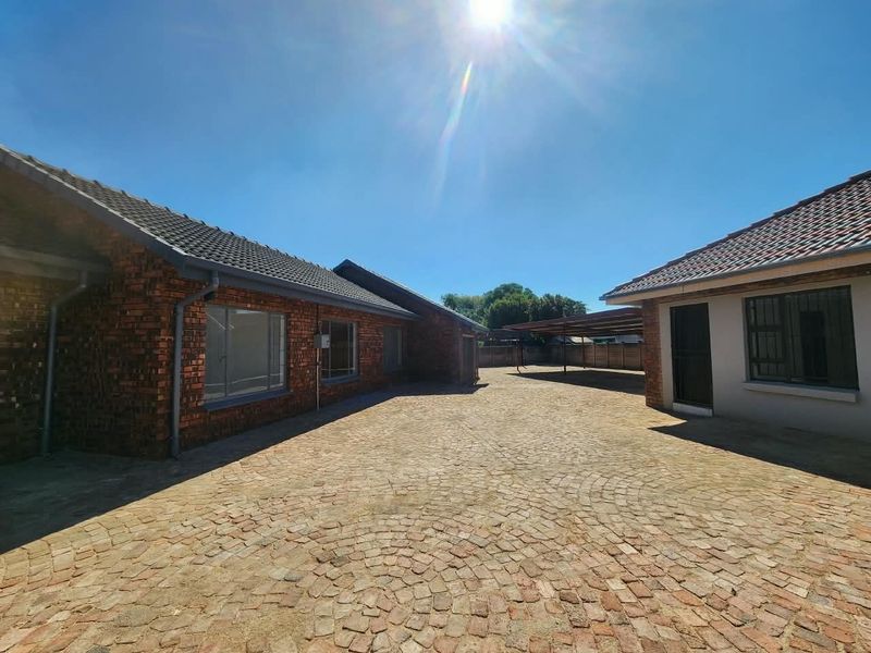 Spacious paved courtyard area between office buildings featuring a covered carport and well-maintained brickwork exterior.