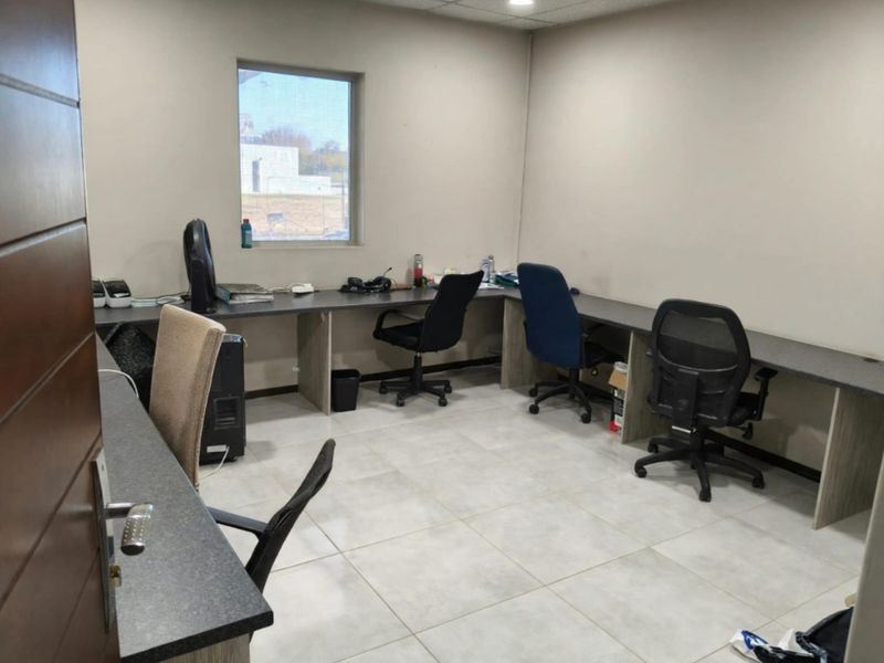 A functional office space featuring built-in desk workstations, tiled flooring, and recessed ceiling lighting, providing a practical environment for professional use.