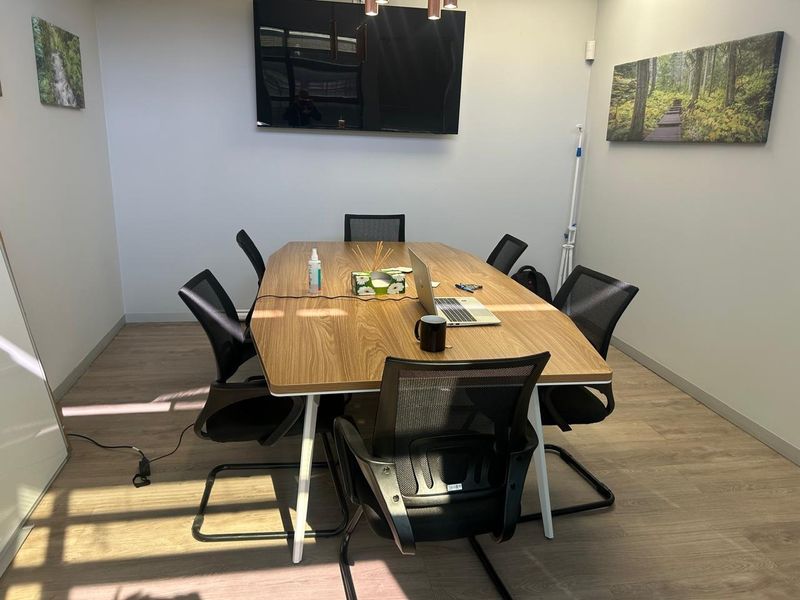 A functional office meeting room featuring modern laminate flooring and neutral wall finishes, suitable for professional collaboration.