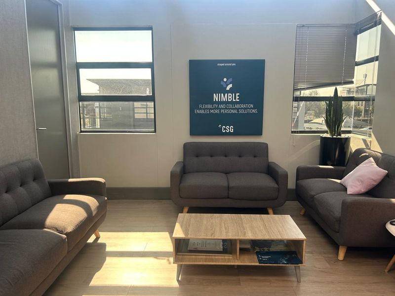 A bright office waiting area featuring large windows with venetian blinds and modern laminate flooring.