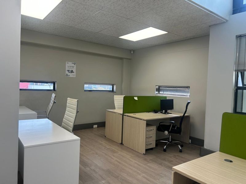 A functional office space featuring laminate flooring, acoustic ceiling tiles, recessed lighting, and horizontal window blinds.