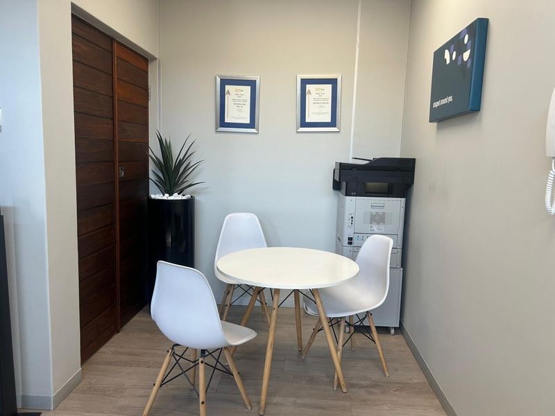 A compact office space featuring light laminate flooring and wooden double doors, suitable for a small meeting area or private workspace.