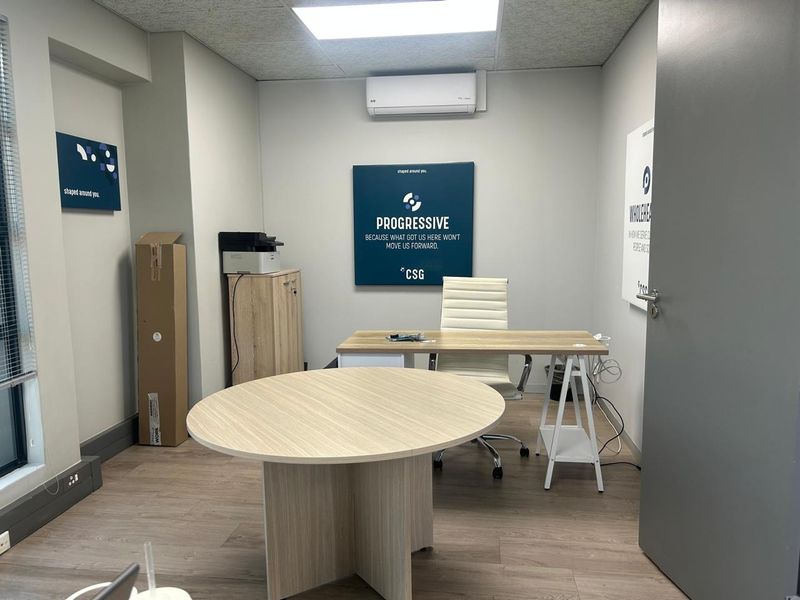 A well-maintained private office space featuring laminate flooring, a split-system air conditioner, and neutral wall finishes, suitable for professional use.